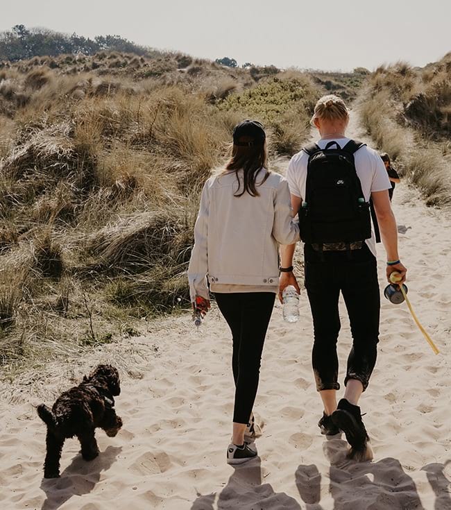 Couple walking their dog on a beach path 