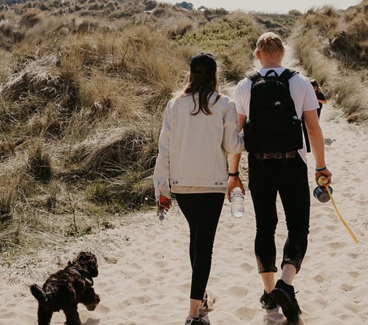 Couple walking their dog on a beach path 